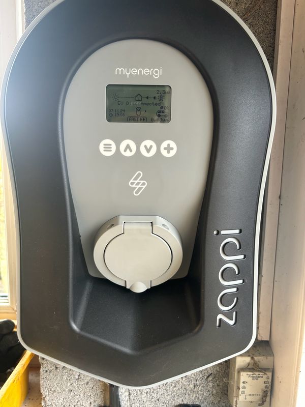 Dark grey myenergi zappi untethered EV charger installed indoors beside a window by AK Electrical